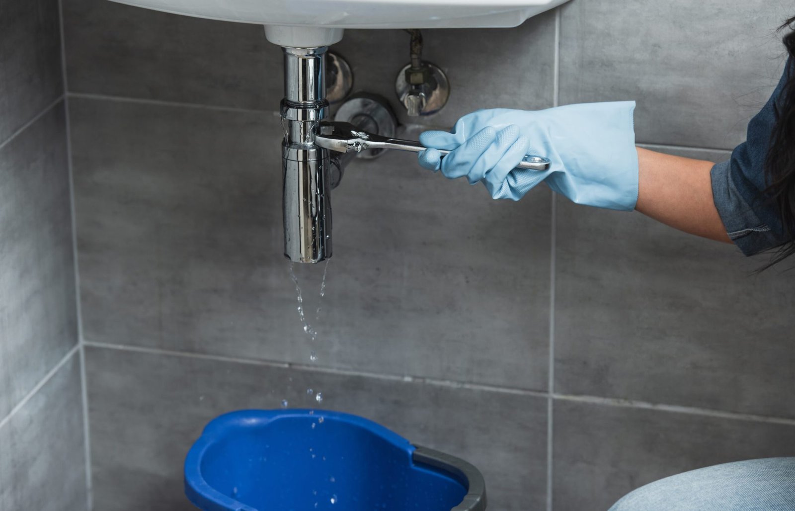 Partial view of woman in blue rubber glove using wrench