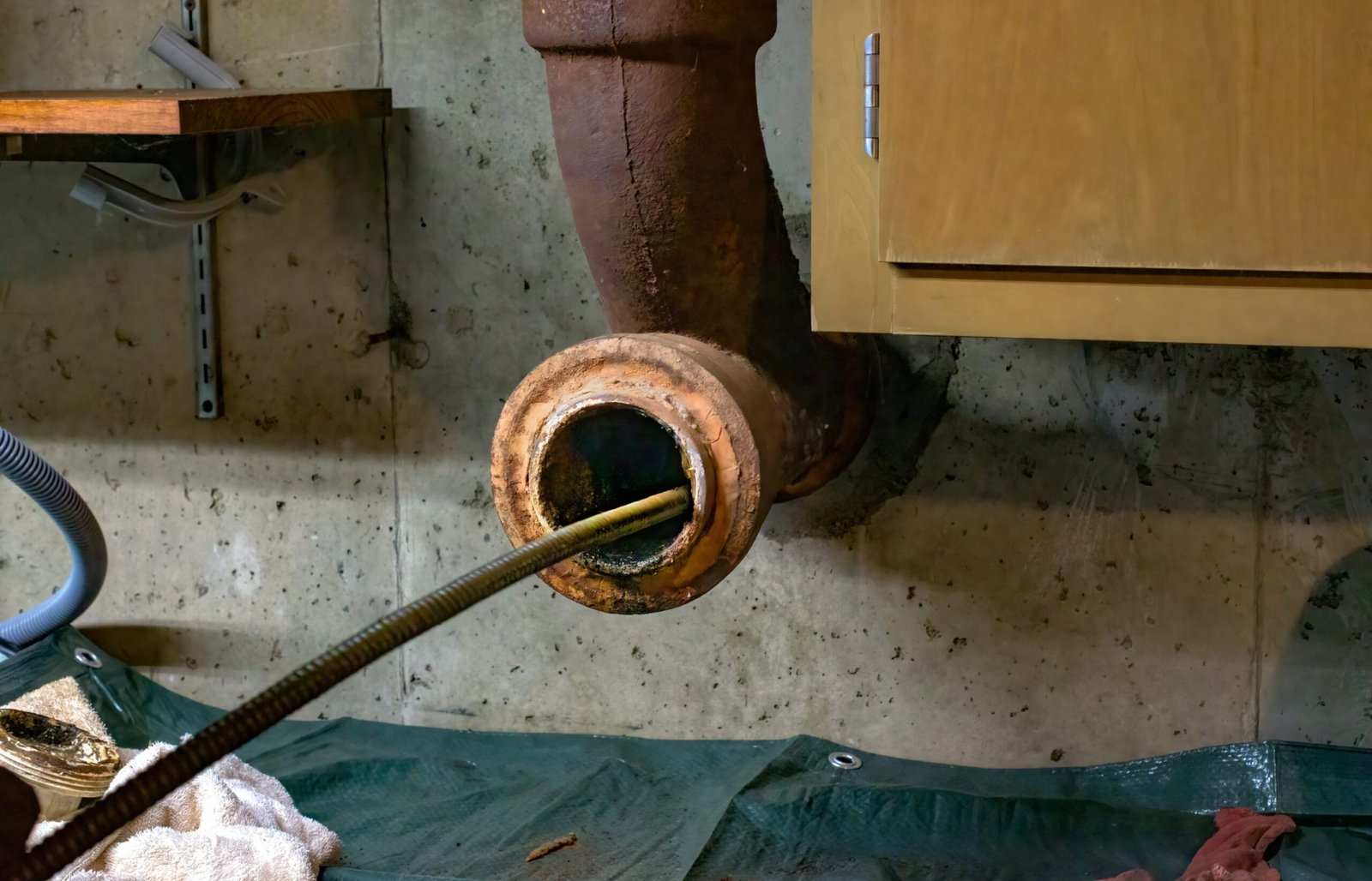 Hands of a plumber as he runs a camera scope and cleaning machine through the main pipe to unclog the drain to the Septic System.  Hard-working tradesman.